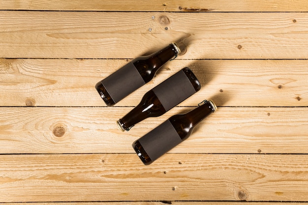 Elevated view of three beer bottles on wooden background