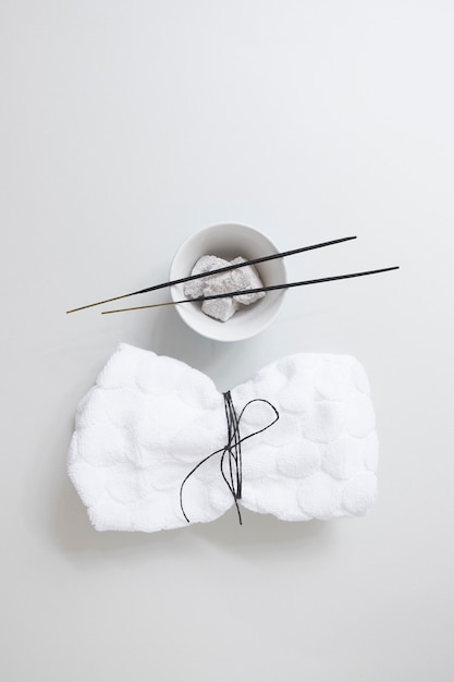 Elevated view of tied napkin near incense stick and pumice stone on white background