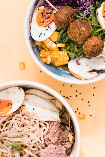 An elevated view of traditional asian noodles bowls on beige backdrop