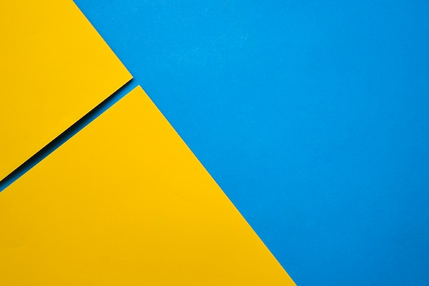 Elevated view of two yellow craftpapers on blue surface