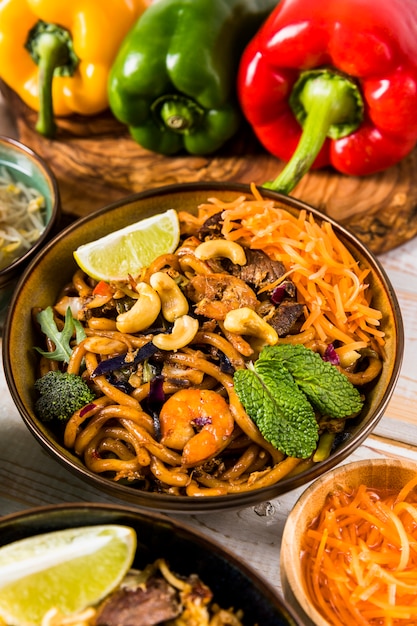 An elevated view of udon noodles with nuts; broccoli; mint; lemon and shrimp