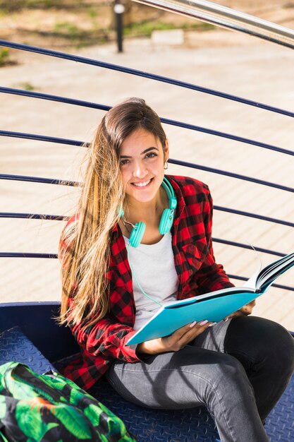 An elevated view of university student sitting on staircase holding book in hand