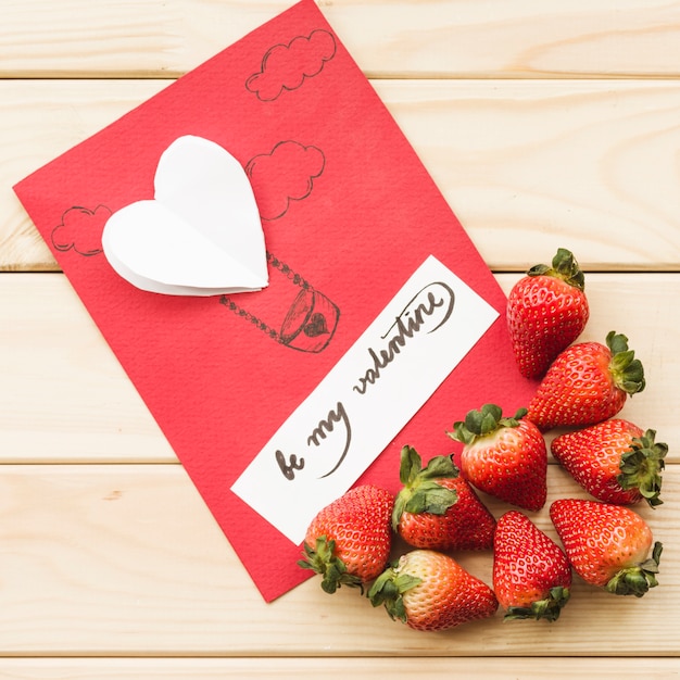 Elevated view of valentine day card with strawberries on wooden background