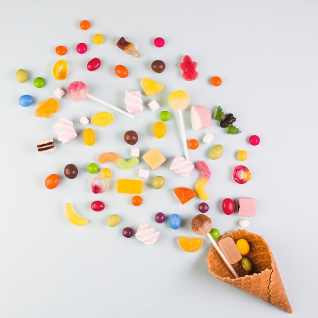 Повышенный вид различных конфет с мороженым вафельный конус на белом фоне
