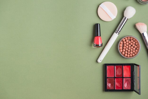 Elevated view of various makeup products on green background