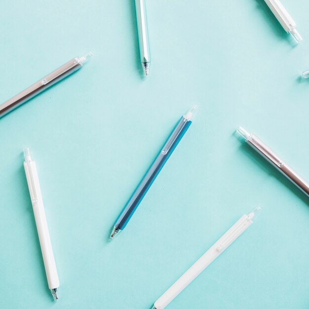 Elevated view of various pens on turquoise colored background