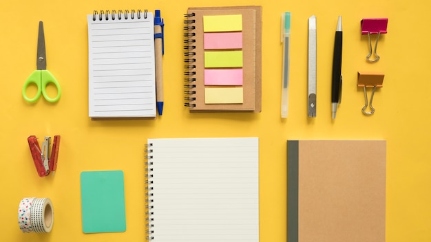 Elevated view of various stationeries on yellow backdrop