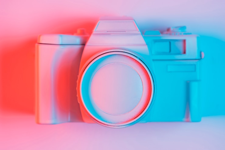 मुफ़्त फोटो elevated view of vintage camera on pick surface with blue light and shadow