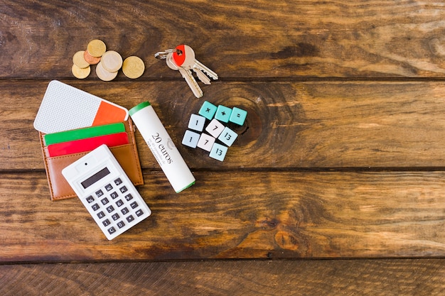 Elevated view of wallet with cards, calculator, math blocks, key, and coins on desk