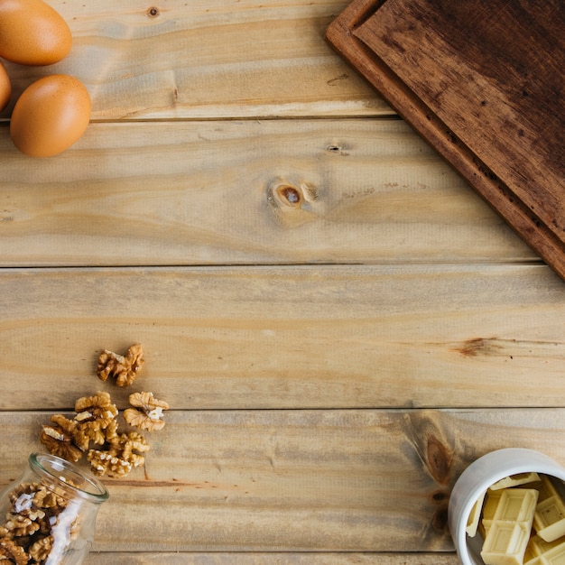 Elevated view of walnut; chocolate pieces and brown eggs on wooden background