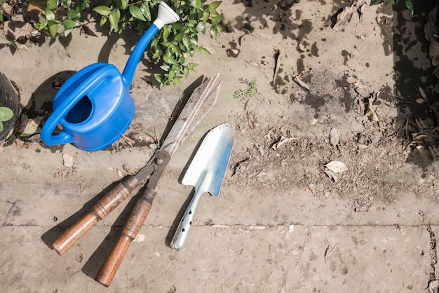 Elevated view of watering can; hand shovel and gardening scissors in greenhouse