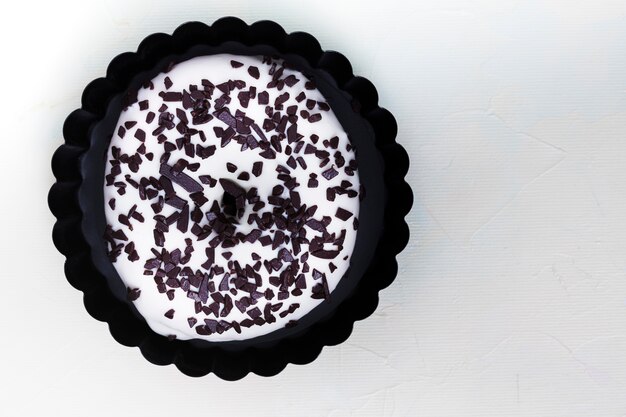 An elevated view of white donut with chocolate chips toppings on white backdrop