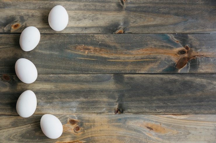 Free Photo elevated view of white eggs forming curve shape on wooden backdrop