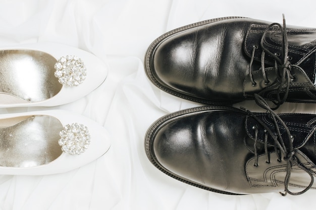 An elevated view of white high heels and black shoes on scarf