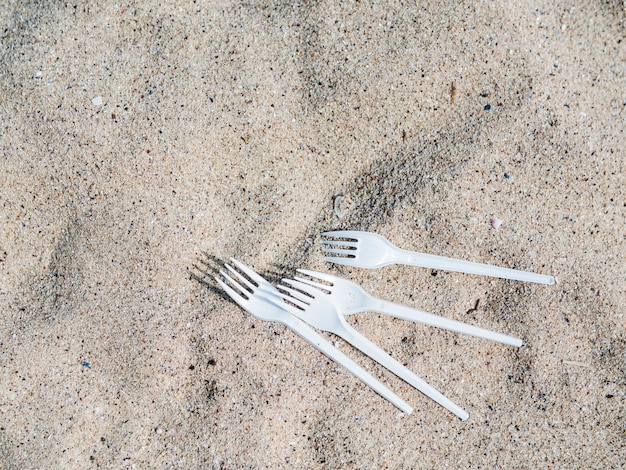Elevated view of white plastic fork on sand