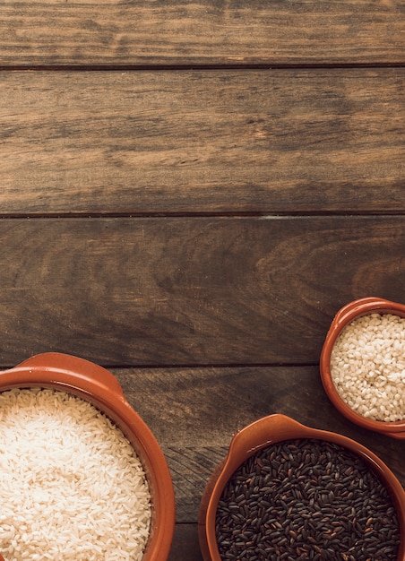 Elevated view of white rice and black rice grain bowls on wooden backdrop