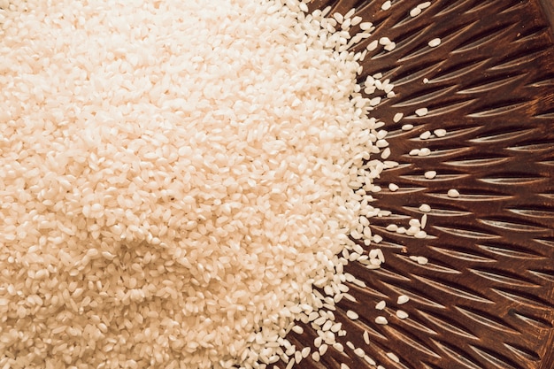 Elevated view of white rice grains on wooden plate