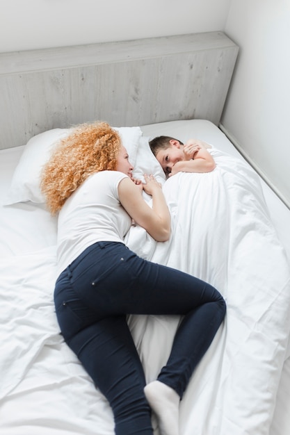 Elevated view of woman and her son lying on bed looking at each other