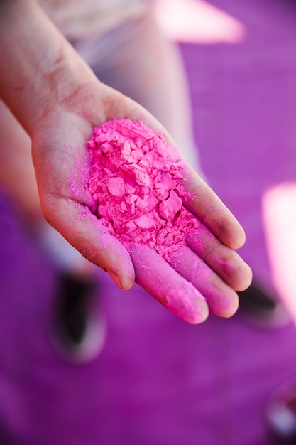 An elevated view of woman's hand holding pink holi color