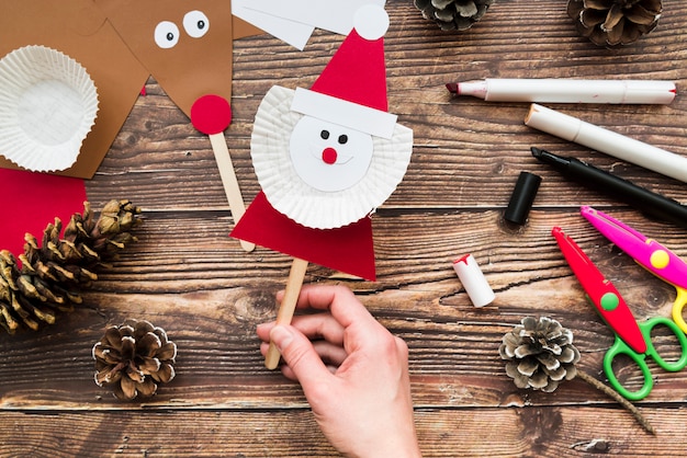 An elevated view of woman's hand holding santa claus prop over the table