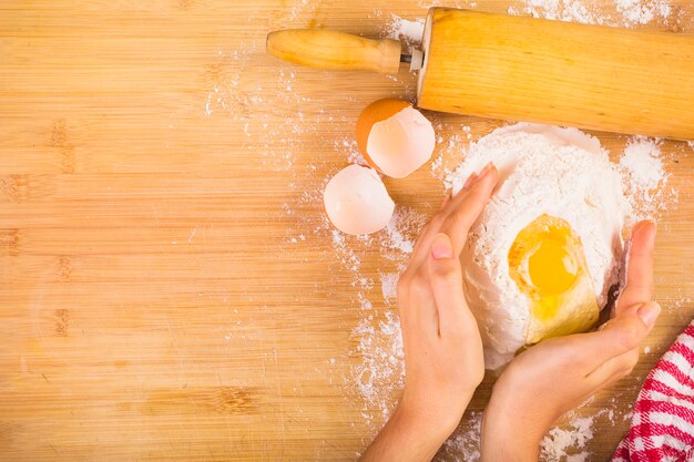 Elevated view of woman's hand mixing flour with egg