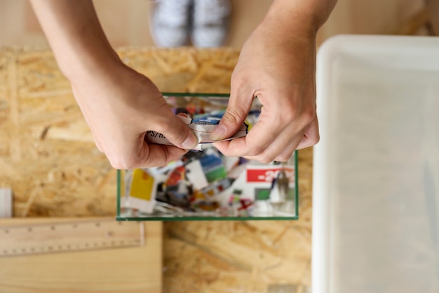 Elevated view of a woman's hand tearing paper over glass container