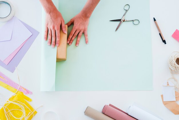 An elevated view of a woman wrapping the gift box on white backdrop