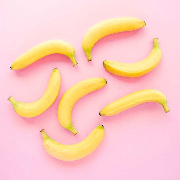 An elevated view of yellow bananas on pink backdrop