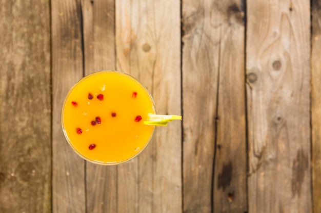 Elevated view of yellow cocktail in martini glass on wooden background