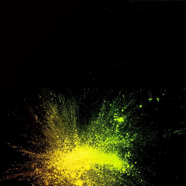 Elevated view of yellow color powder explosion on black background