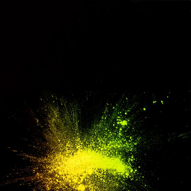 黒の背景に黄色の色粉爆発の立面図