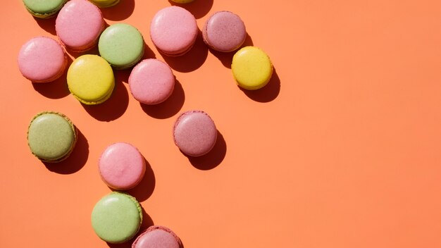 An elevated view of yellow; pink and green macaroons on colored backdrop