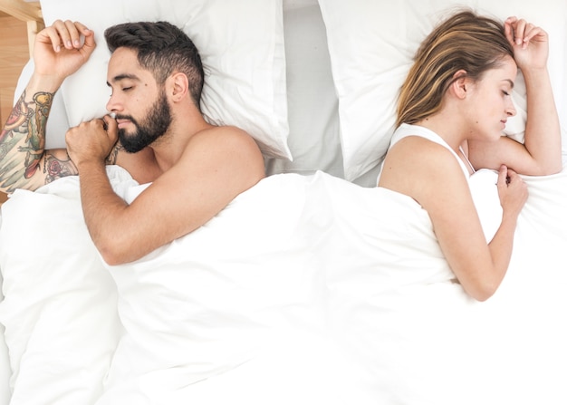 Elevated view of young couple sleeping on bed