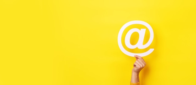Email sign in hand over yellow background, panoramic layout
