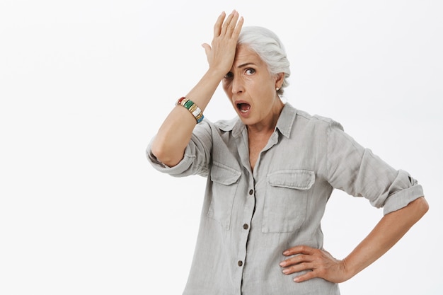 Free photo embarrassed and shocked senior woman slap forehead and looking concerned