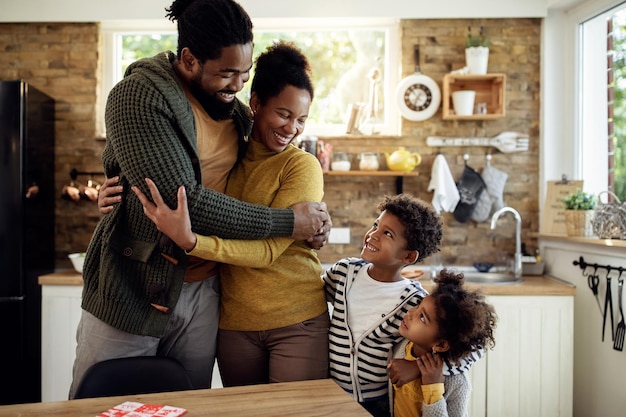 Семья афроамериканцев в объятиях разговаривает на кухне