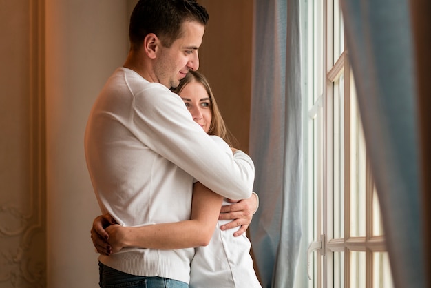 Embraced couple looking through window