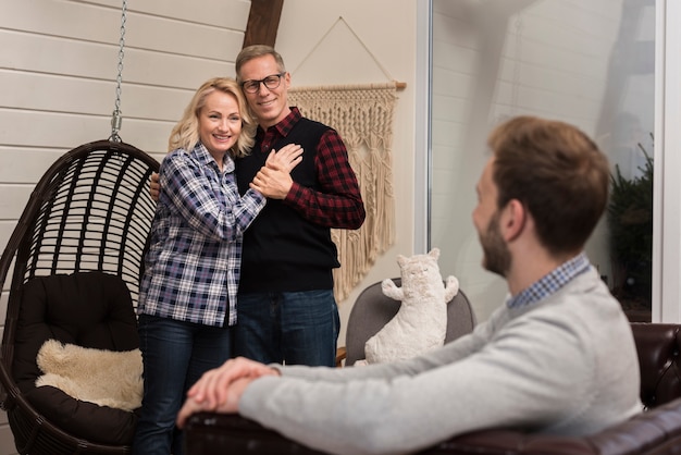 Free photo embraced parents smiling at son on sofa