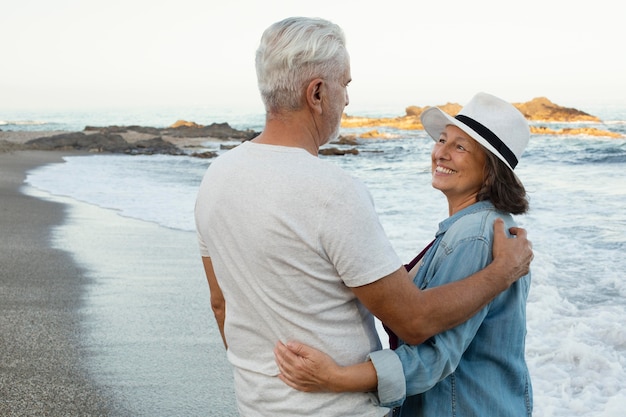 Free photo embraced senior couple enjoying their day at the beach