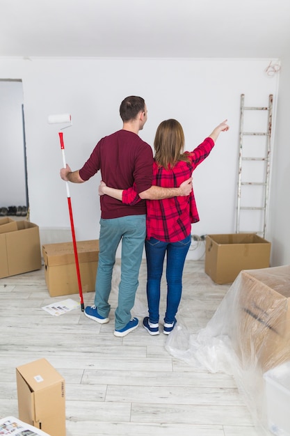 Embracing couple pointing at wall