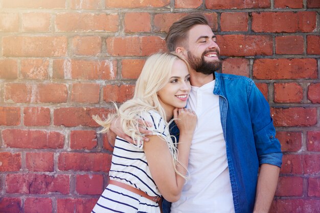 Embracing couple standing in front of brick wall