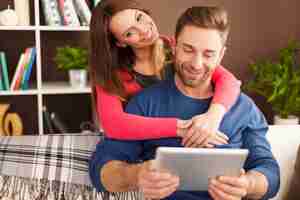 Free photo embracing couple using digital tablet in living room