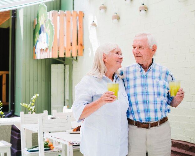 Embracing elderly couple drinking juice in cafe