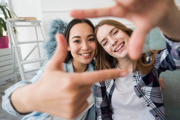 笑顔でselfieのような手でフォトフレームを作る女の子を抱きしめる