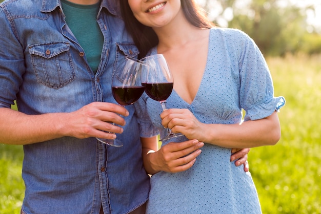  Embracing multiethnic couple clinking glasses in park