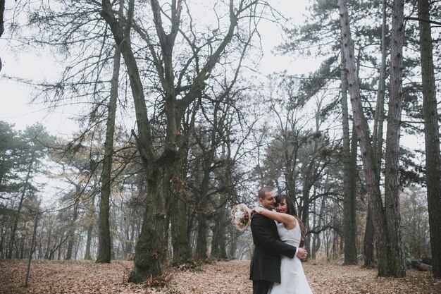 Embracing newlyweds in leafless forest