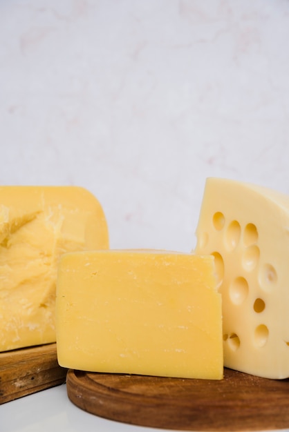 Emmental and gouda cheese pieces on wooden chopping board