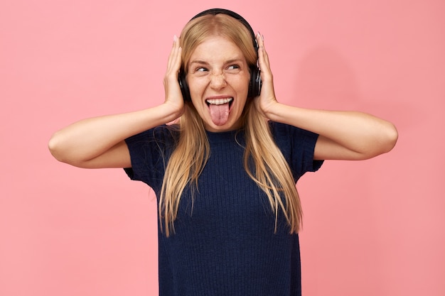 Emotional adorable teenage girl enjoying favorite music tracks in wireless headphones