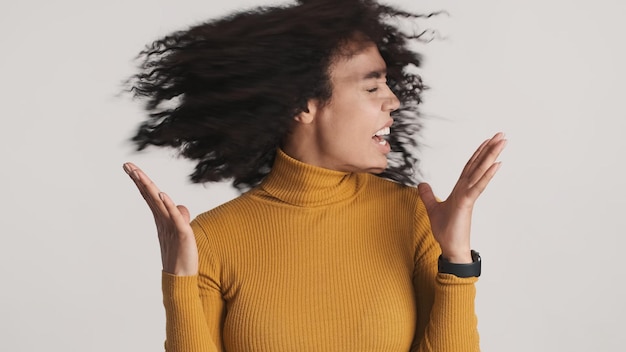 Free photo emotional african american woman with dark fluffy hair waving head on camera over white background