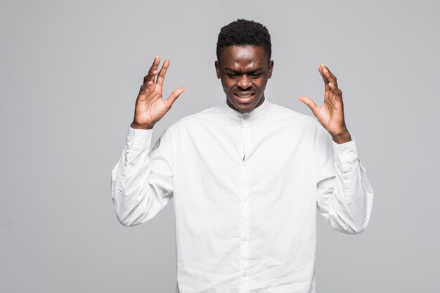 Emotional angry young african man standing isolated over gray background.